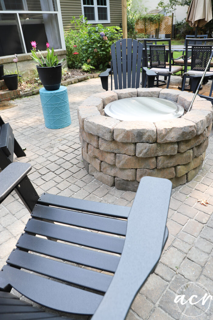 stone firepit on patio with black chairs around it