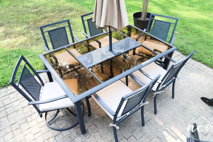 table chair set painted black with tan seat cushions and tan umbrella