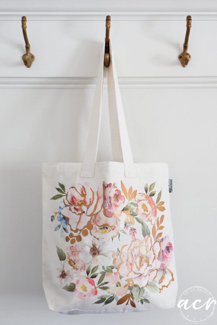 white tote hanging on hook with pink flowers on front