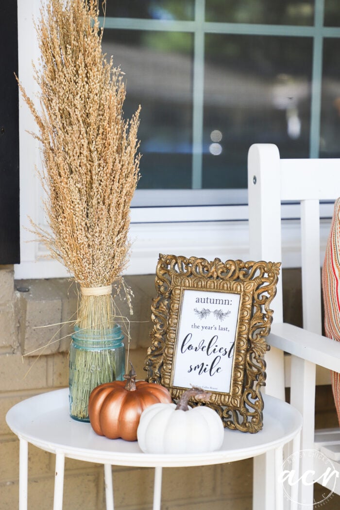 little round white table with framed fall printable, pumpkins and dried wheatgrass