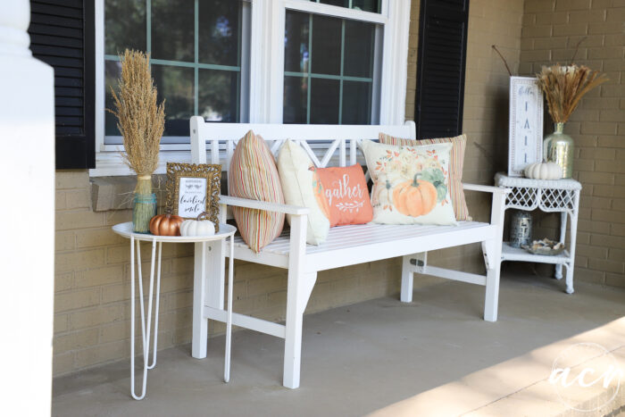 white bench with orange pillows white tables on each side