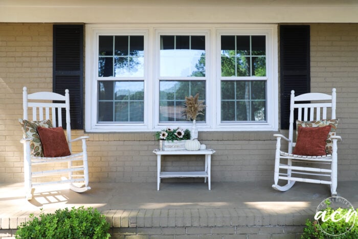 white rockers with rust pillow white table in front of window