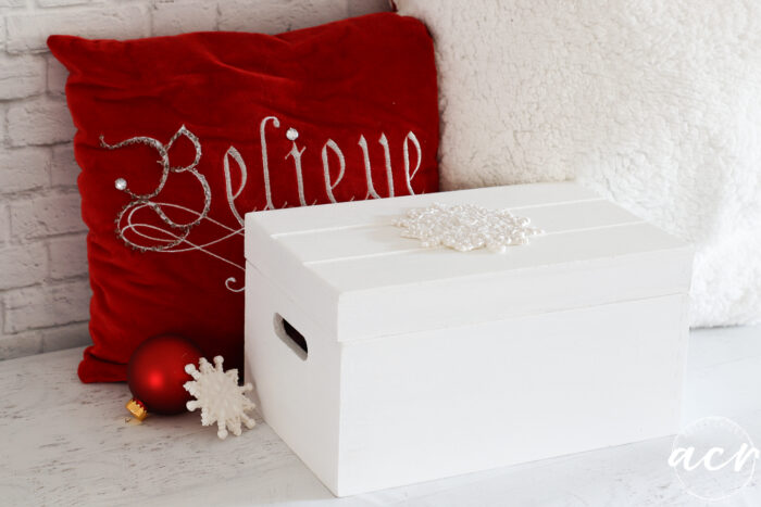 red pillow with white box and ornaments