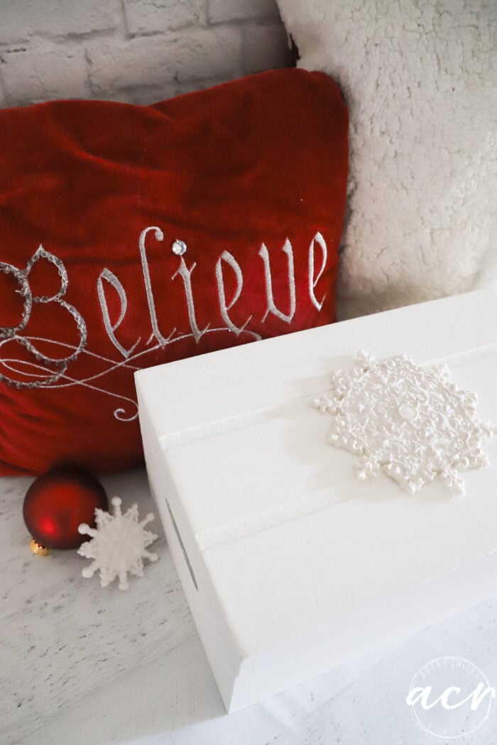 red believe pillow with white box