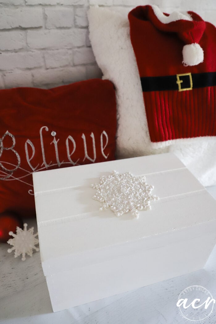 white snowflake box with red pillow and red Santa sweater for small dog