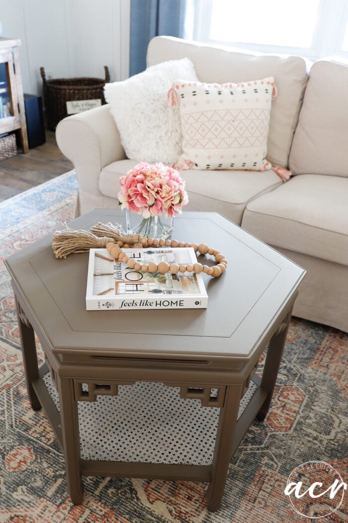 table with book and flowers on top by couch