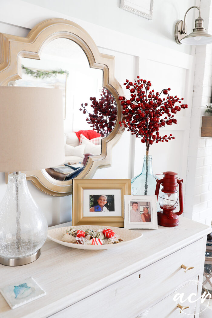 red berry bunch in aqua vase, red lantern on dresser in living room