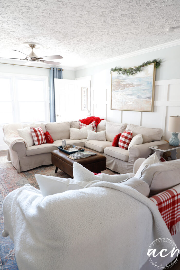 living room sectional couch with red and white pillows and throws