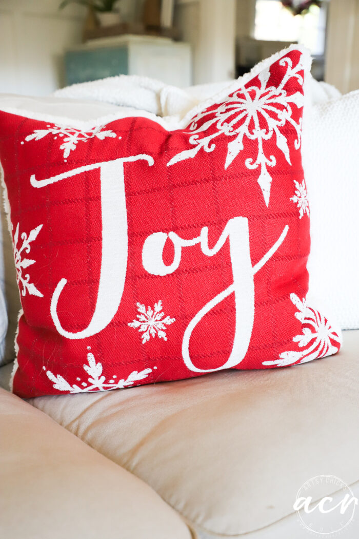 red and white joy pillow on couch