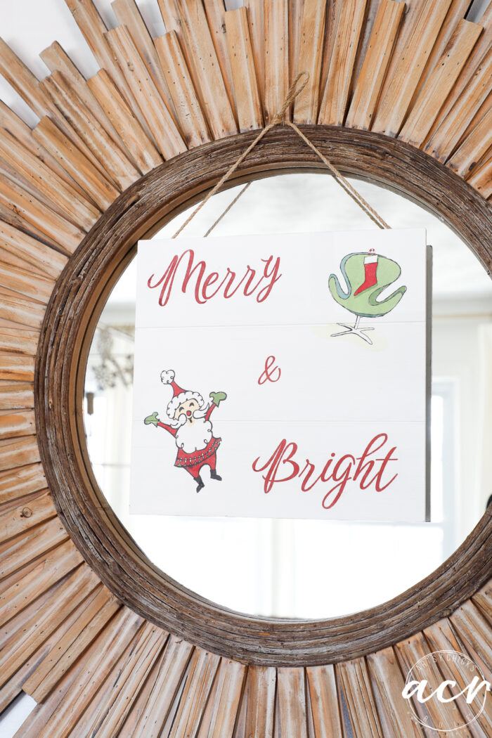 wood starburst mirror with merry and bright sign hanging on it