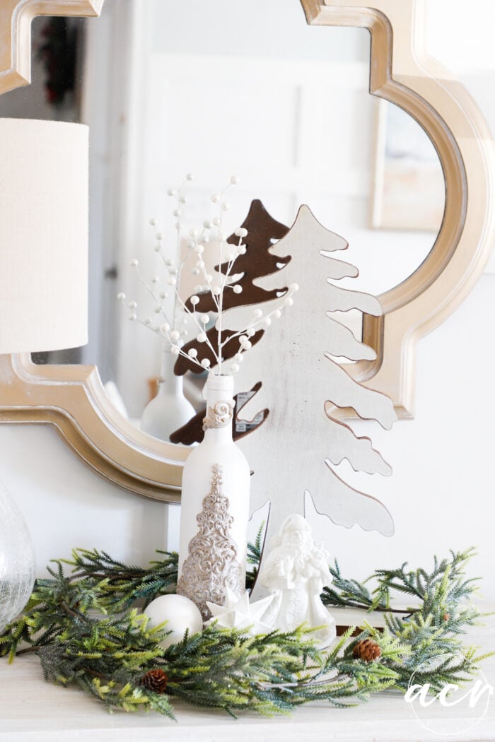 white bottle with gold tree in center piece with greenery