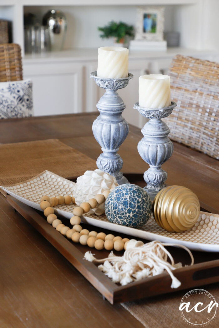 two candlesticks on table with cream colored candles