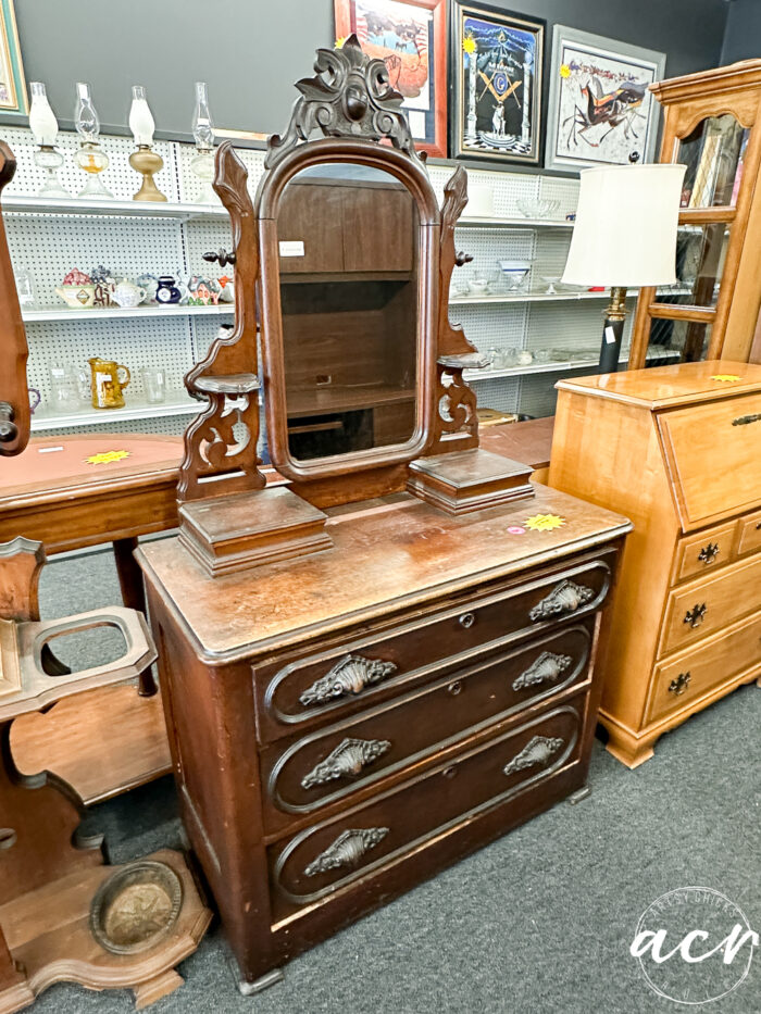 wood dresser with very heavy, ornate pulls and decorative mirror
