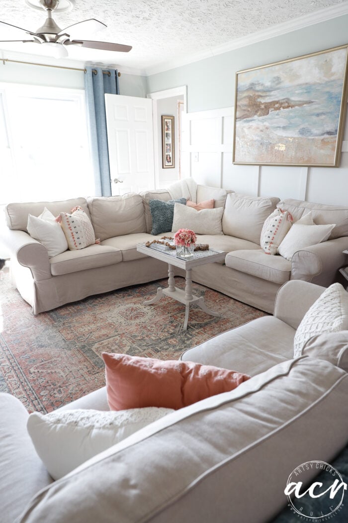 living room with tan couches and tiled table styled