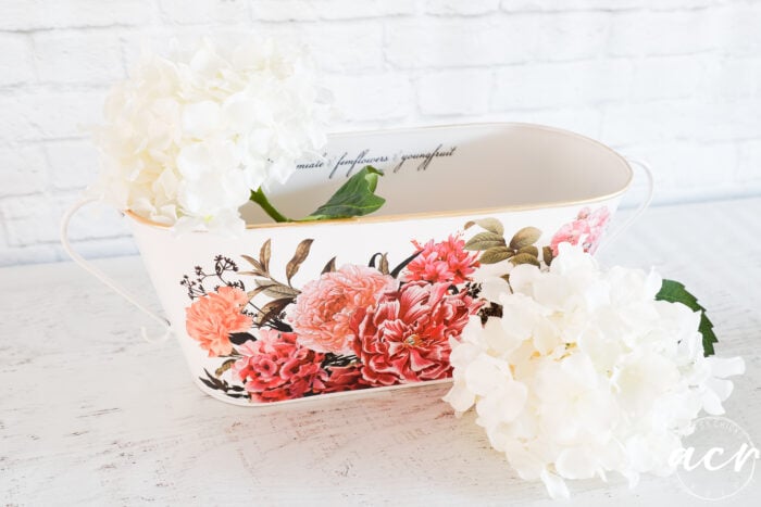 white container with pink florals and white flowers inside