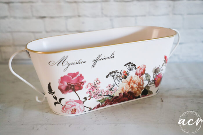 white container with pink florals and words