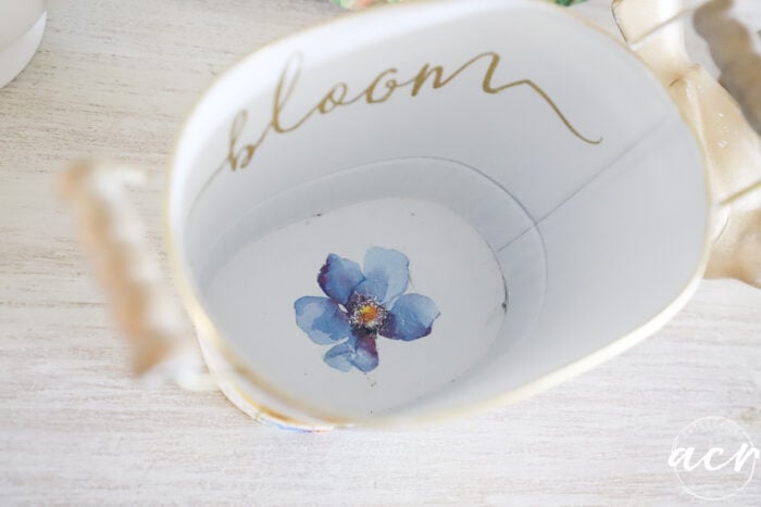inside tin is blue flower on the bottom with the word bloom in side of inside
