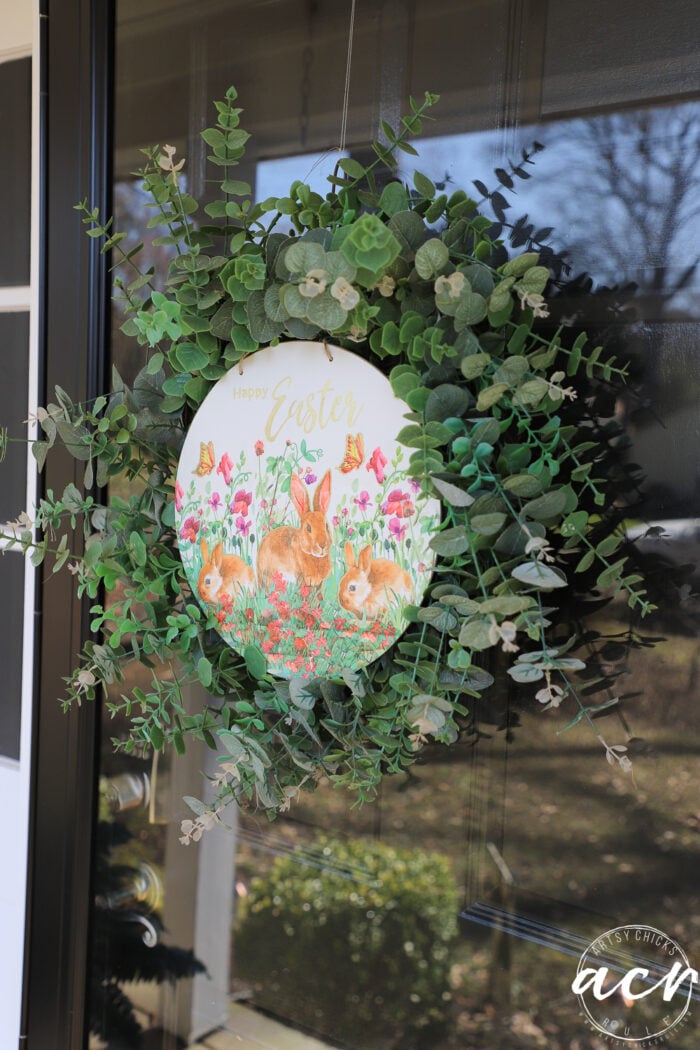 round sign inside of green wreath on door