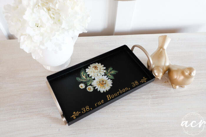 black tray on dresser with gold birds and white florals in white vase