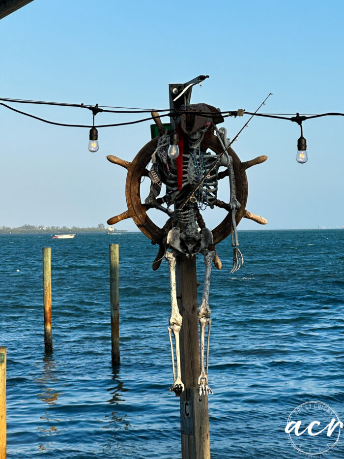ships wheel with skeleton pirate hanging on it