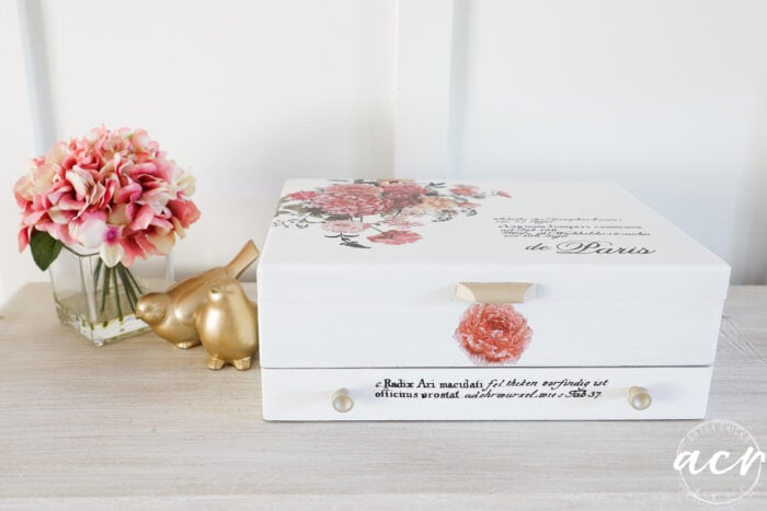 white decorated flatware box with pink vase beside