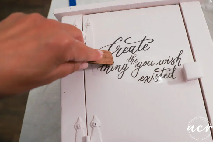 pink small cabinet rubbing on transfer with wood stick