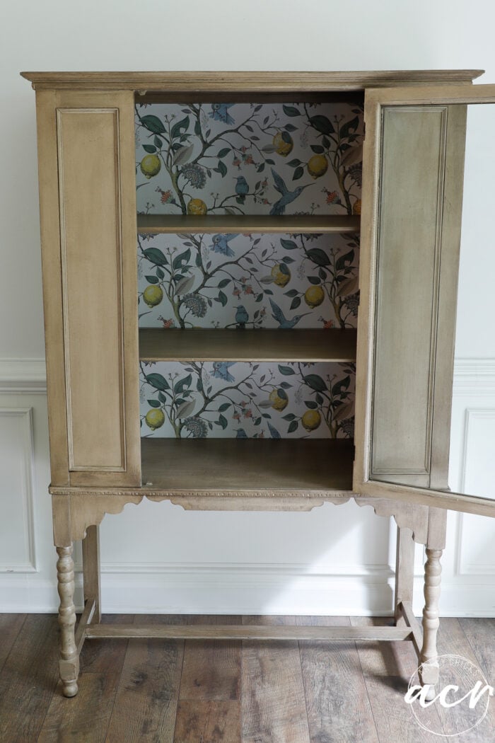 glass door open on cabinet with wallpaper on back