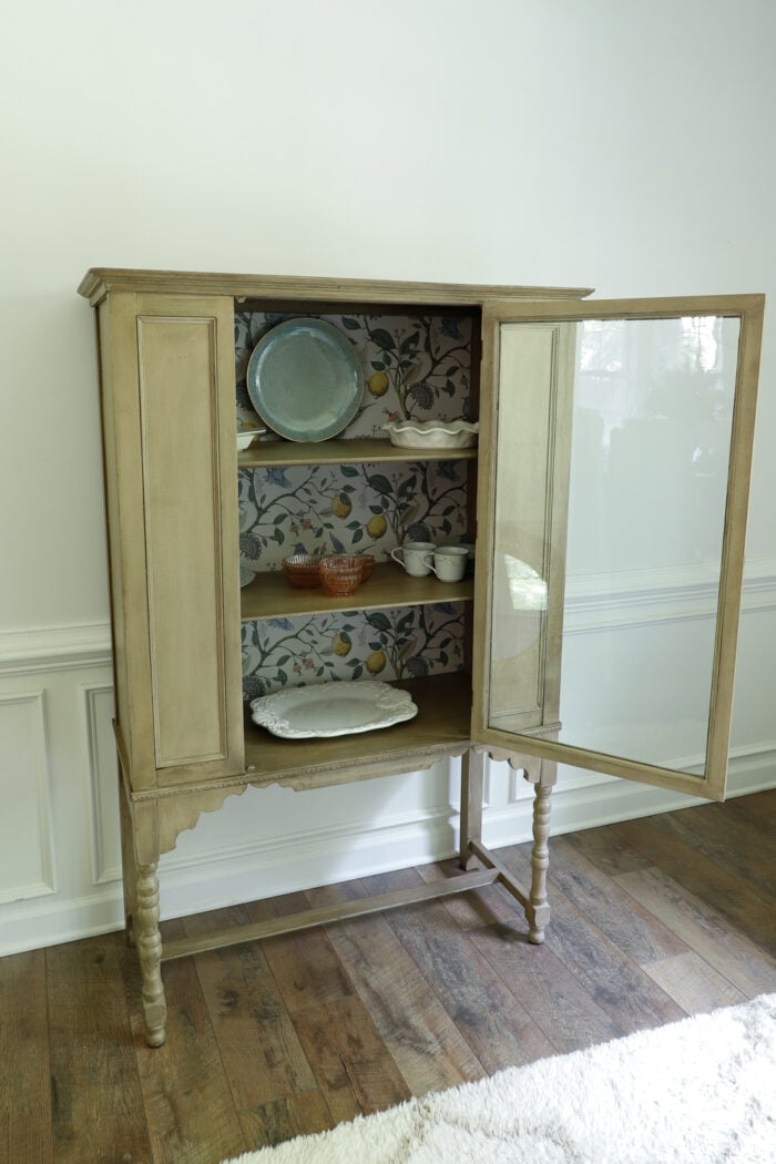 vintage cabinet with glass door open and dishware inside