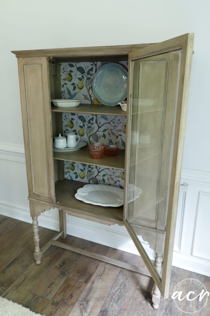 vintage cabinet with door open and dishware inside