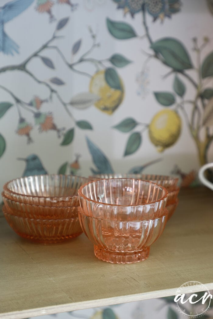 shelf with small pink bowls and wallpaper on back