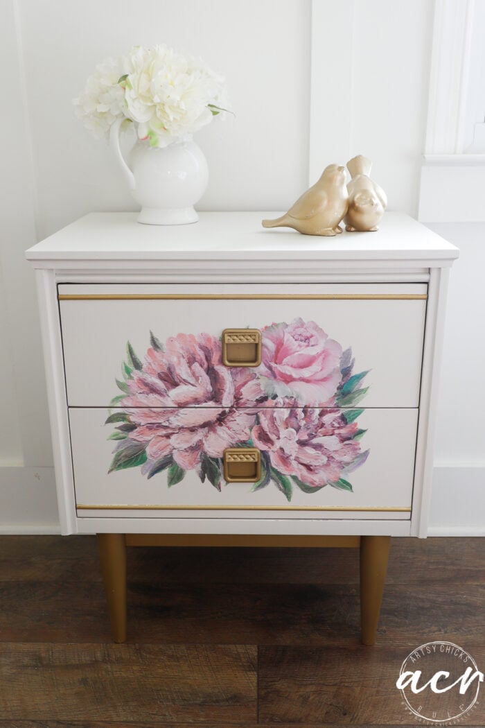 white nightstand with gold and pink floral transfer with white flowers on top in vase and gold birds for decor