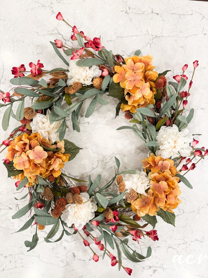 finished wreath on counter, green, off white, reddish and orange florals