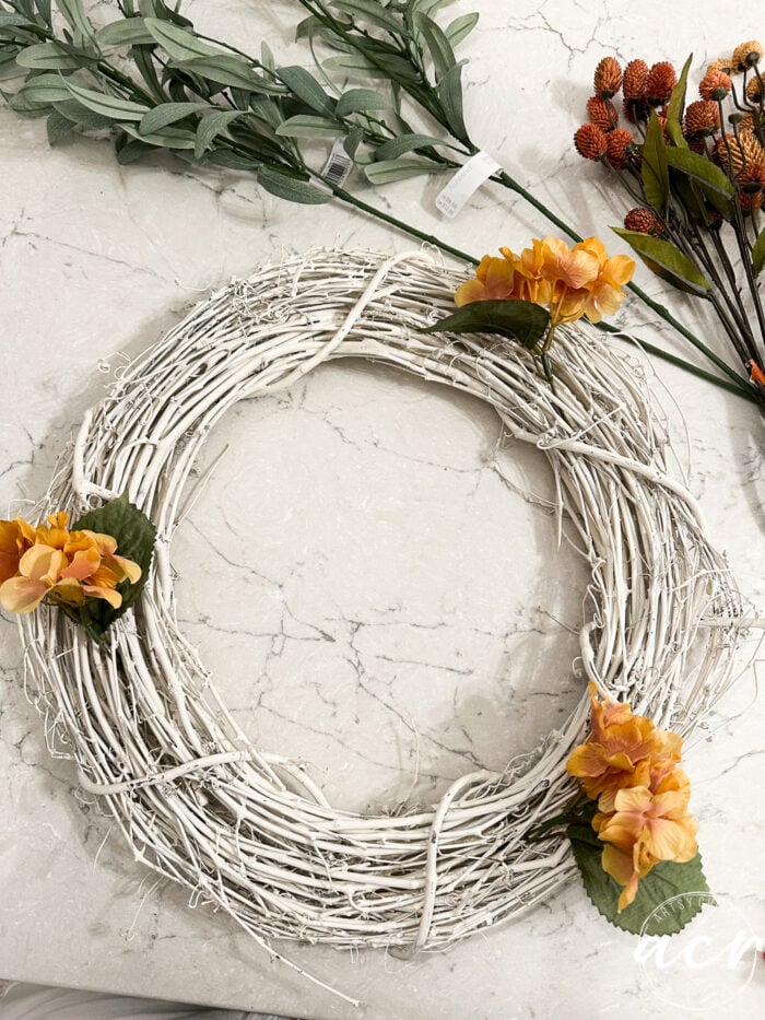 white twine wreath with orange flowers added