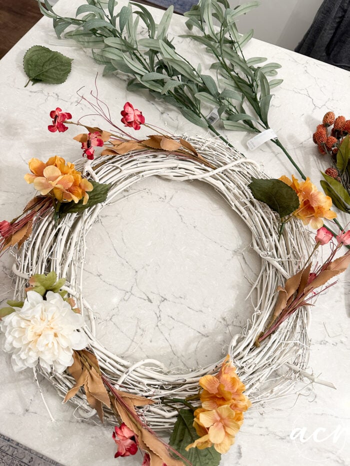 white twine wreath with orange, white and red flowers