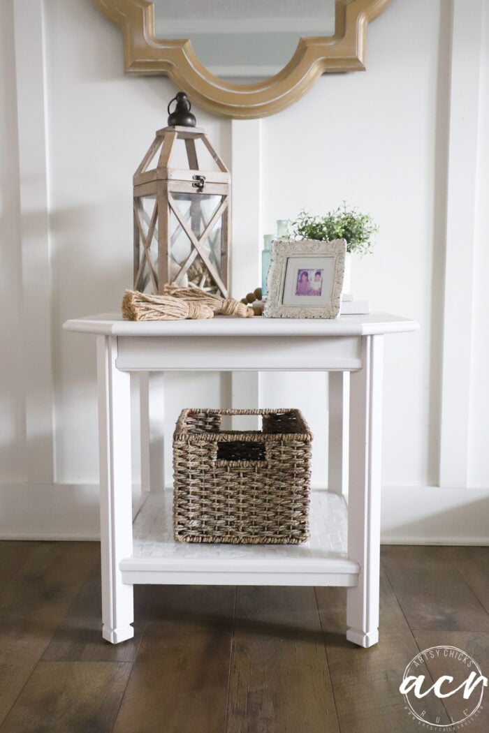 Pequeña mesa auxiliaria blanca con decoración en la parte superior e inferior