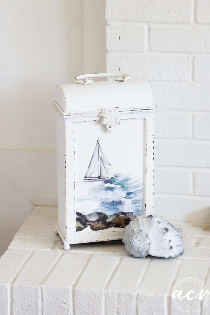 up close of white metal holder with coastal transfers and seashell in front
