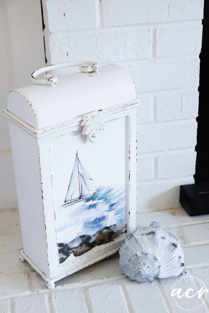 pretty white metal wine holder with seashell in front on brick fireplace 