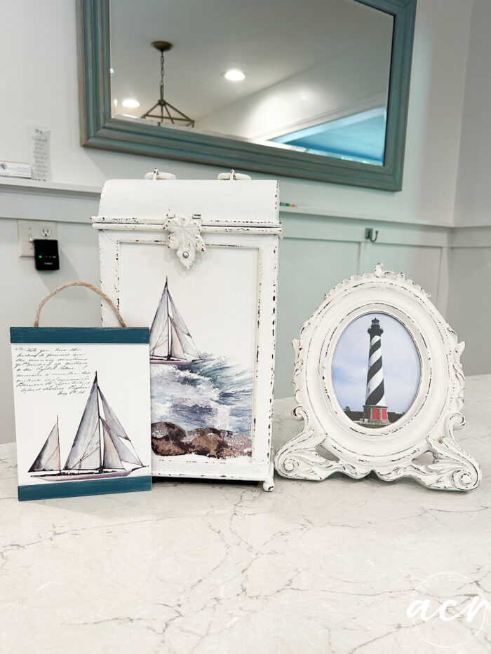 same three smalls painted white with sailboats transfers and a photo of a lighthouse in the frame