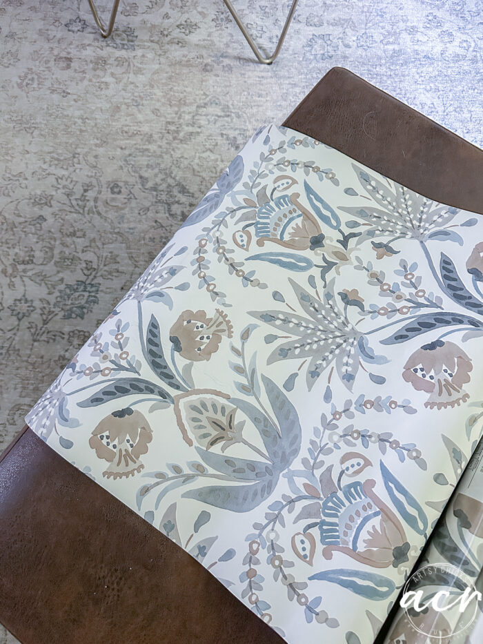 wallpaper roll unrolled partly over ottoman near rug
