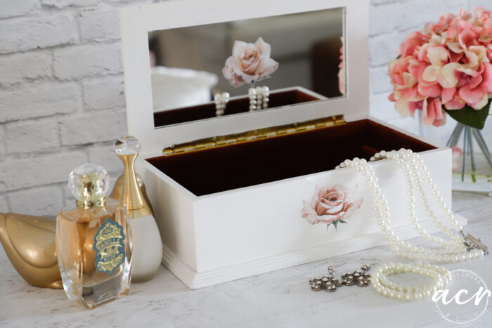 jewelry box open with pearls, earrings and bottles of perfume