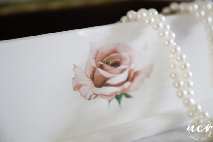 up close of rose on front with pearl necklace 