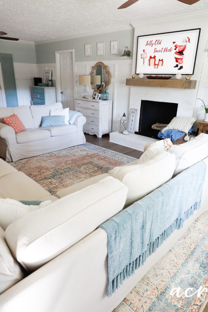tan sectional, fireplace, blue throw and red and coral rug