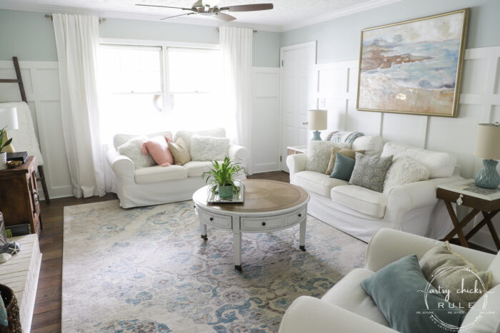 blue and white walls, white curtians, round wood coffee table, white furniture