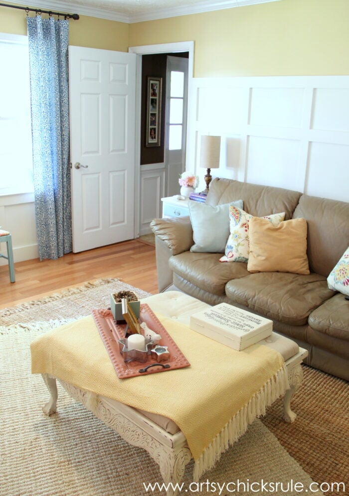 living room with yellow and white walls, light colored rug with blue curtains