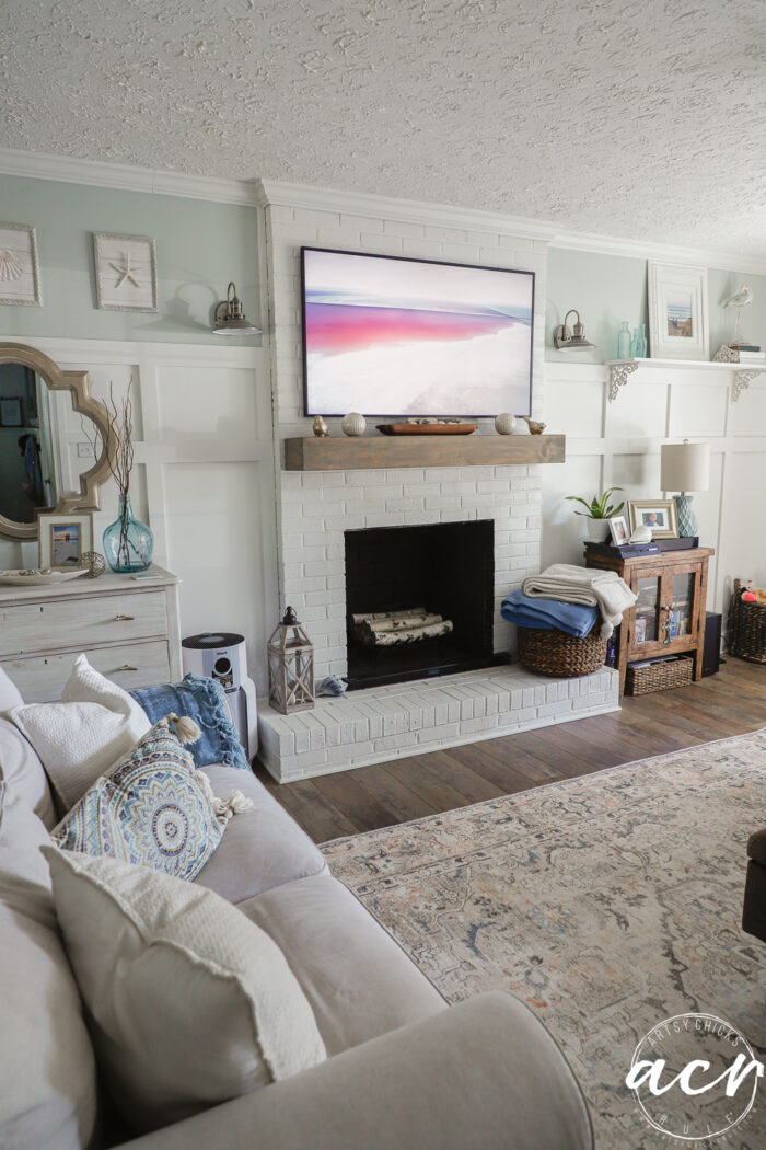 Frame tv over fireplace with photo on it, tan couch