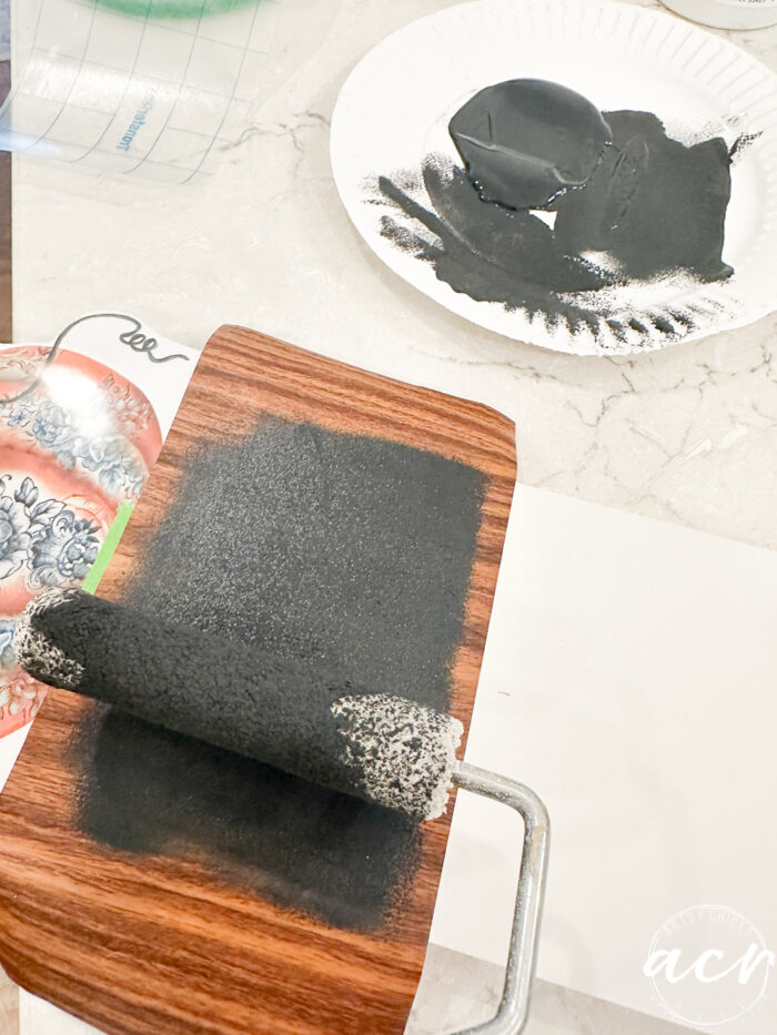 roller rolling black paint onto vinyl cutout