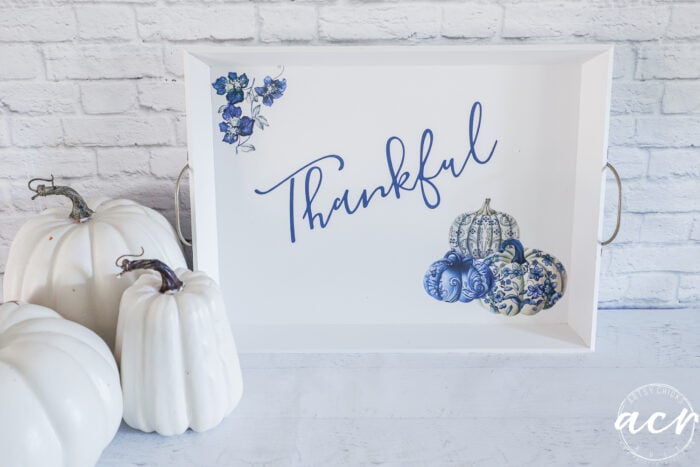 white pumpkins beside white tray with blue pumpkins and thankful