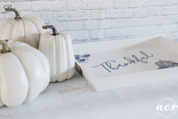 white pumpkins beside white tray with blue pumpkins and thankful