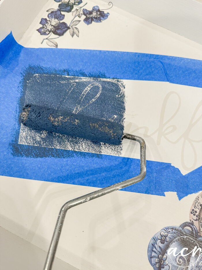 rolling blue paint over stencil