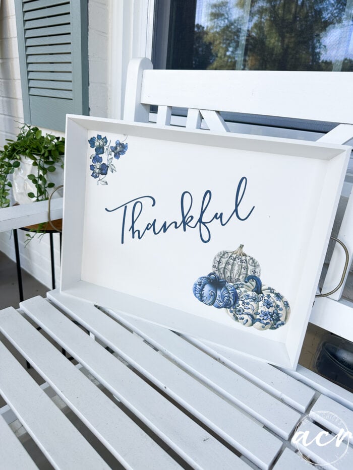 white tray with blue pumpkins and thankful on white bench on porch